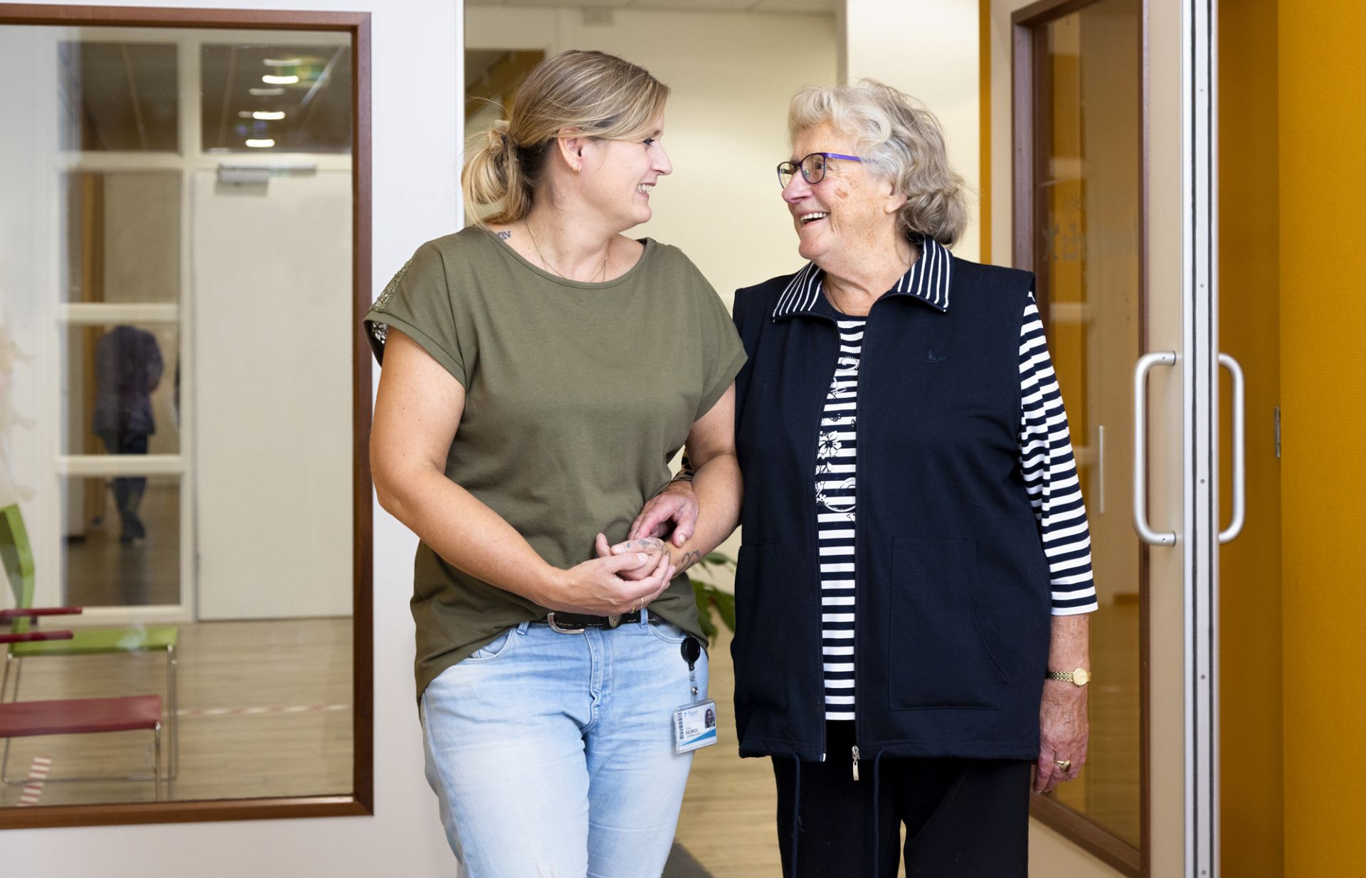 Een medewerker en bewoner lopen samen door de gang