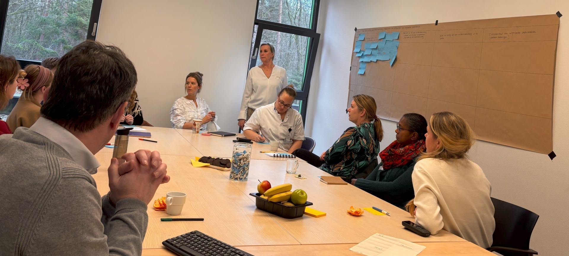 Foto van deelnemers aan overleg rond tafel met brown paper op de achtergrond