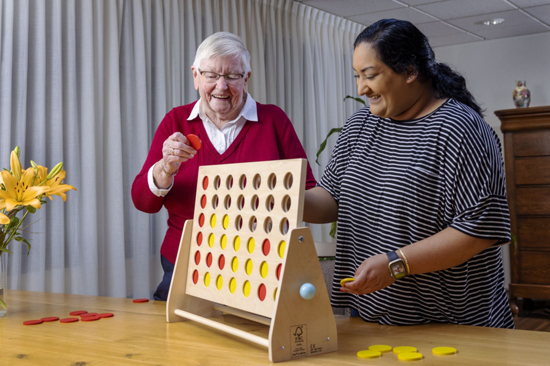 Bewoner en medewerker van Olden Kinholt spelen samen vier op een rij