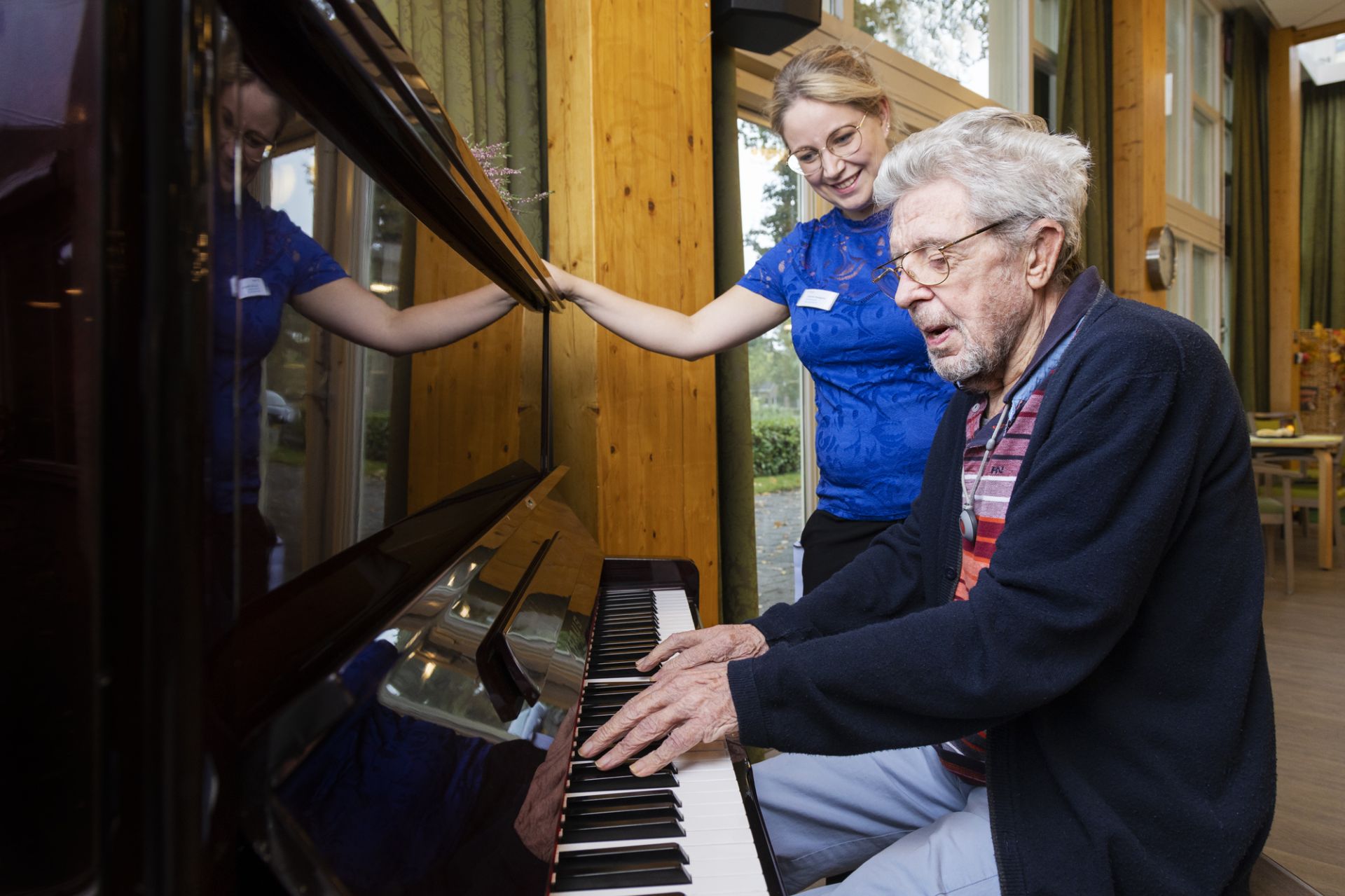 Cliënt speelt onder begeleiding van medeweker een lied op de piano