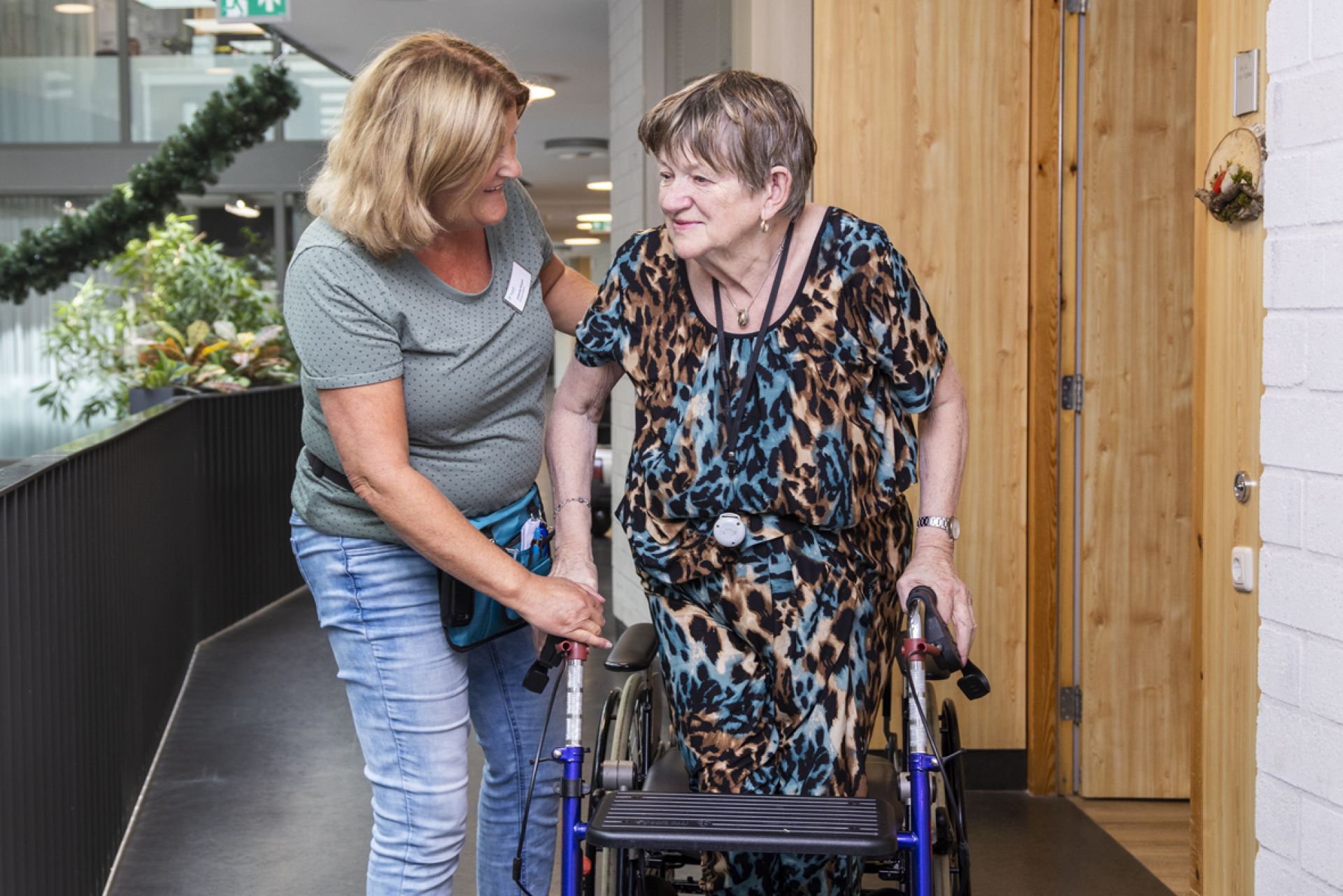 Medewerker helpt bewoner met een rondje lopen in Tonckenshuys.