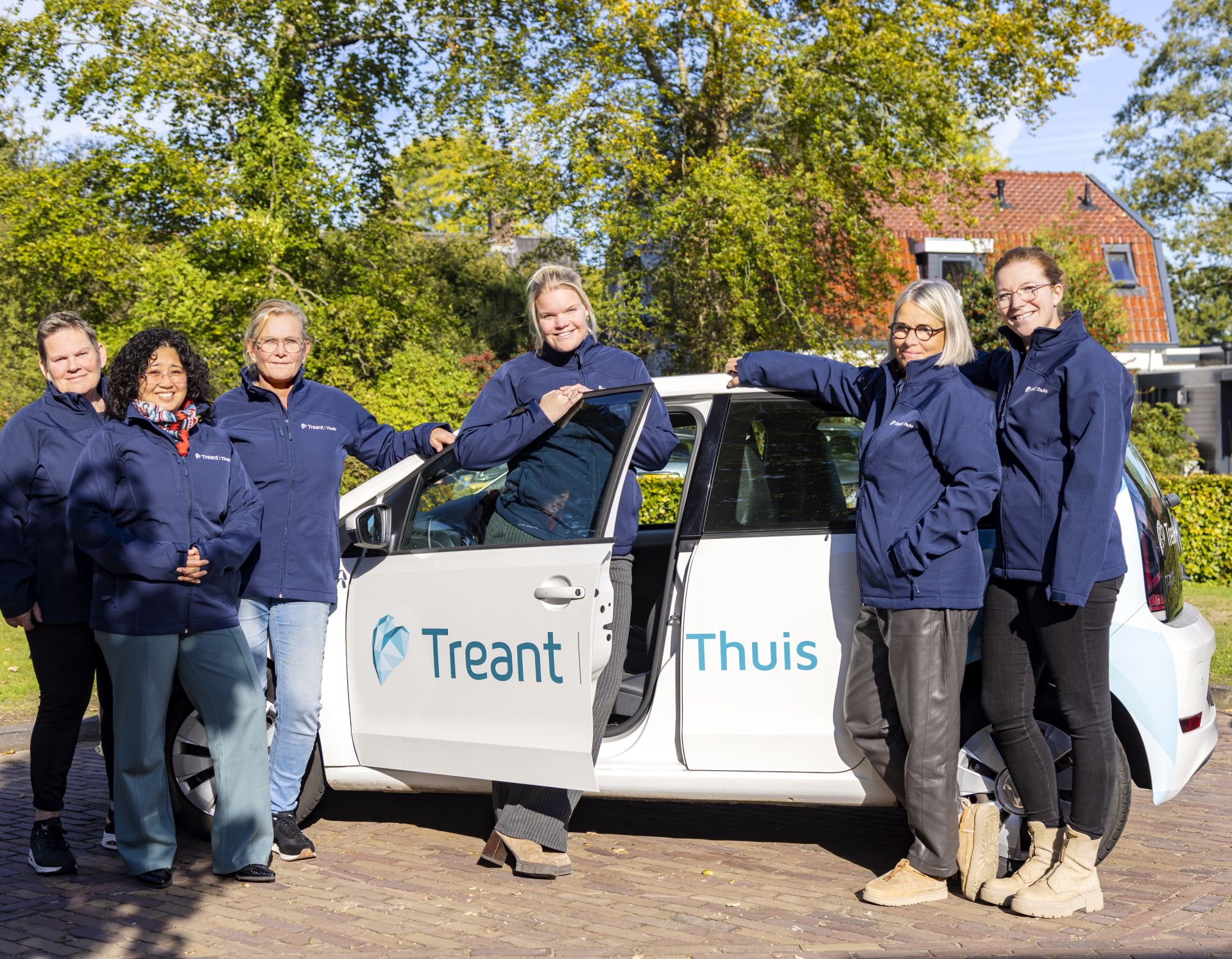 Collega's van Treant Thuis staan bij auto