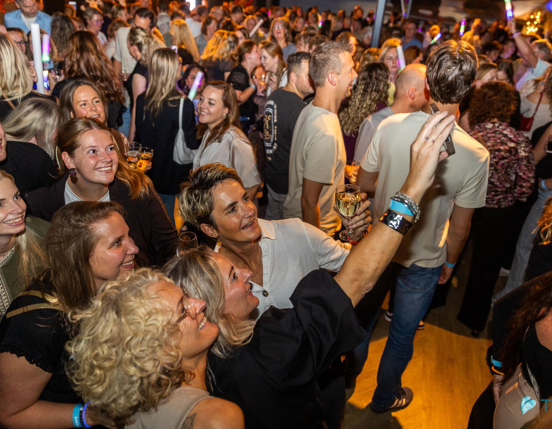 Feestende collega's staan bij elkaar en maken selfie op de dansvloer