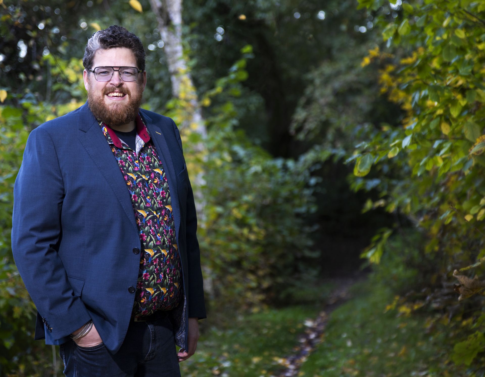 Patiënt Jeroen staat in het bos met zijn handen in zijn zakken