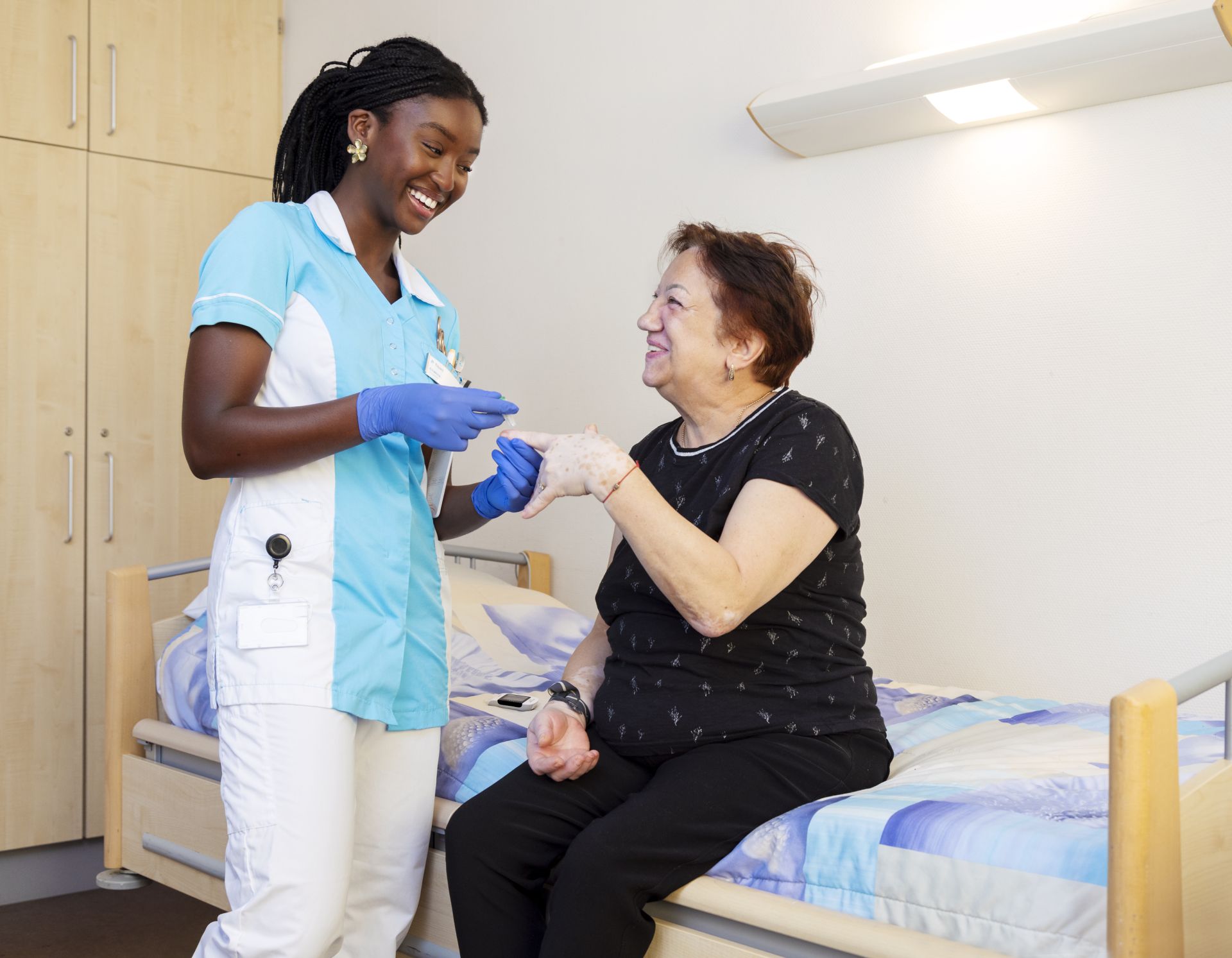 Stagiaire Chakira bloedsuiker meten bij Marja (clíënt)