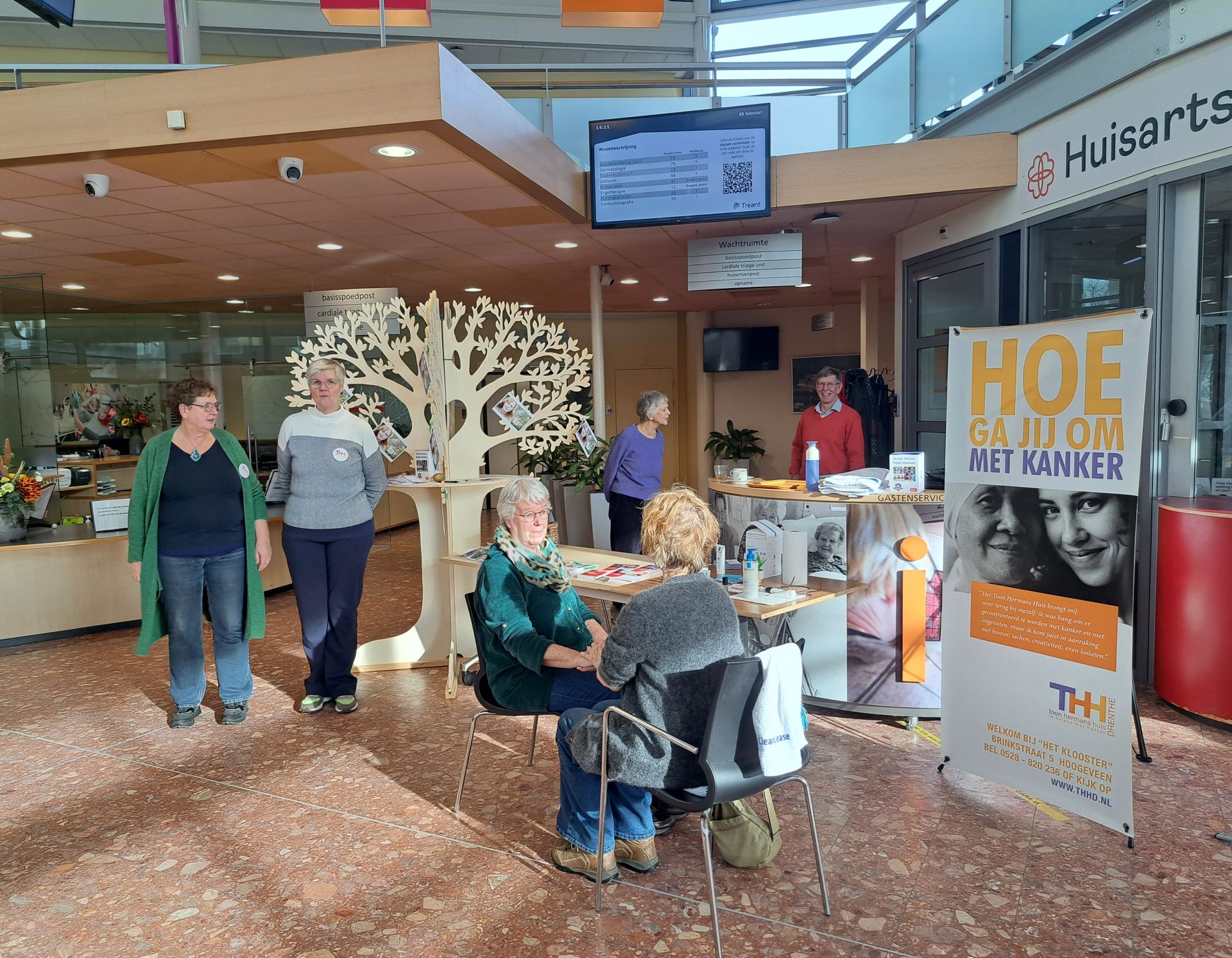 Toon Hermans Huis biedt extra ondersteuning bij kanker. je ziet collega's bij de stand staan en zitten