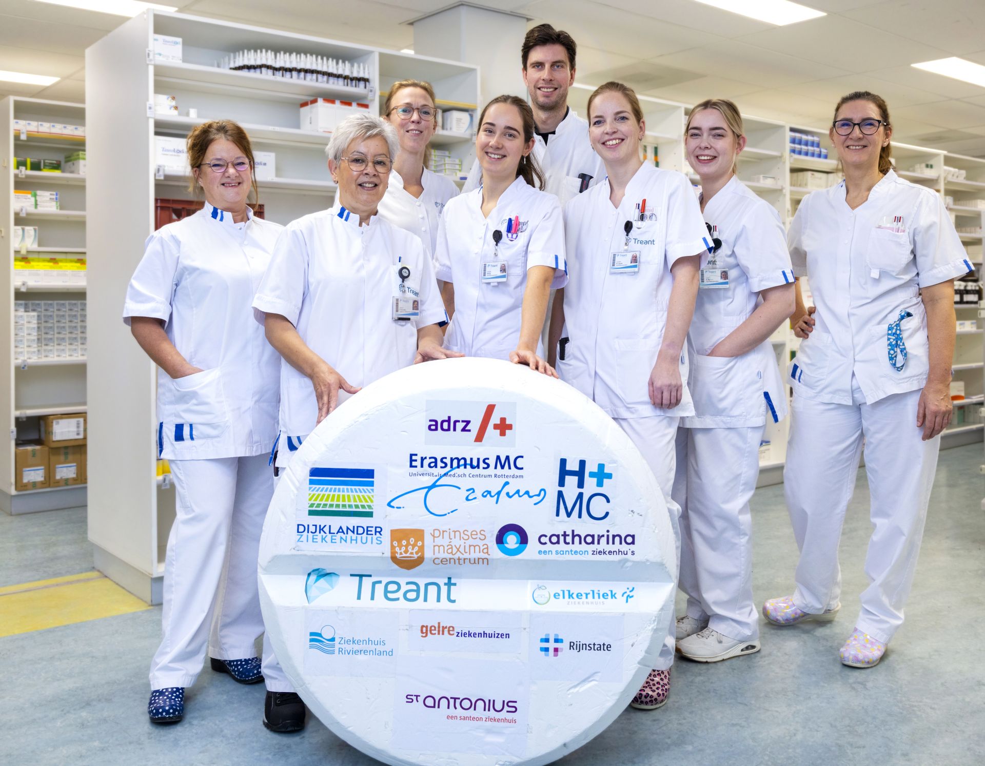 Collega's staan achter een meterhoge paracetamol met daarop logo's van de deelnemende ziekenhuizen