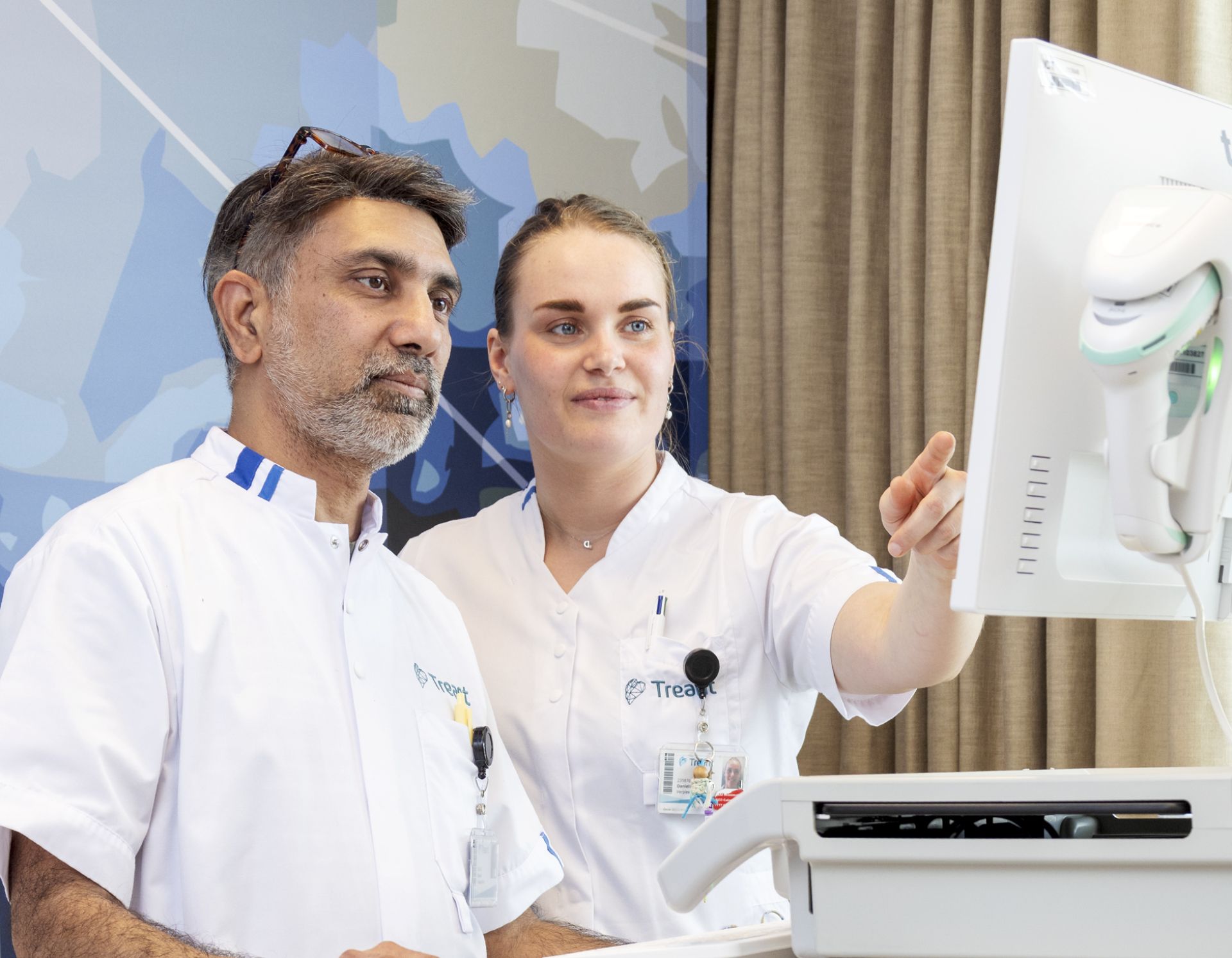 Zorgprofessionals bekijken gegevens op een computer naast een ziekenhuisbed