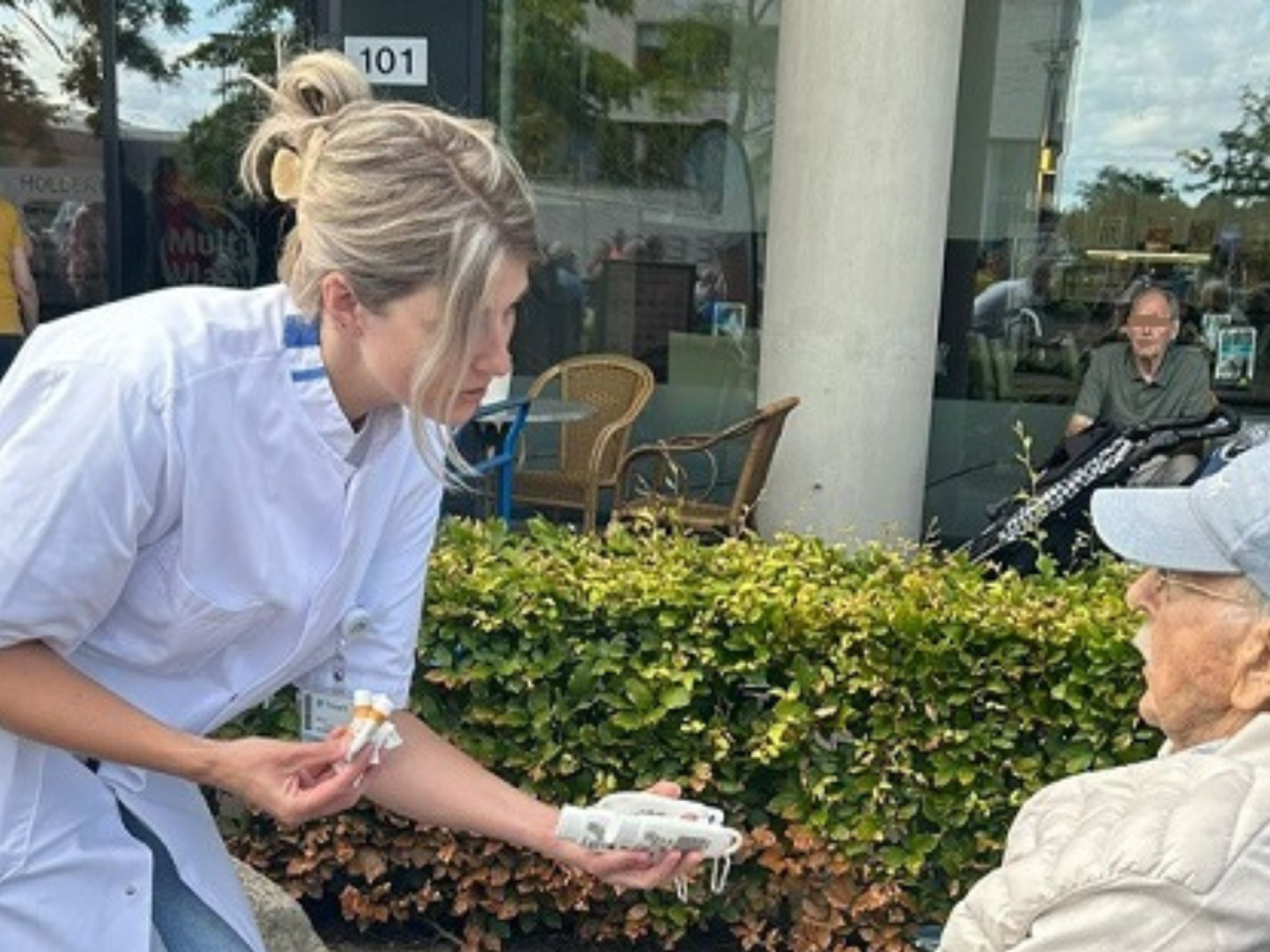 Lorena Tieben deelt zonnebrandcreme uit aan een meneer in een rolstoel tijdens de wandel2daagse van woonzorgcentrum Holdert van Treant