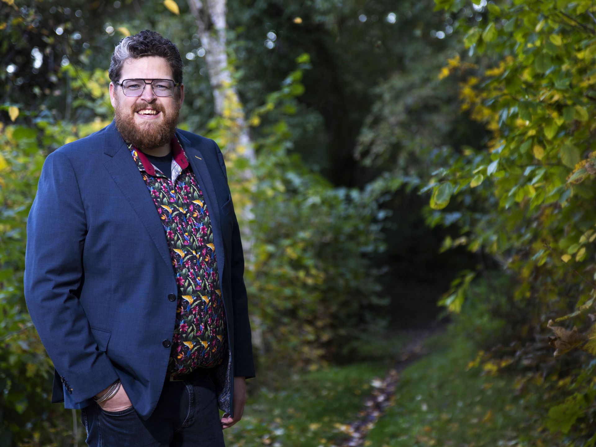 Patiënt Jeroen staat in het bos met zijn handen in zijn zakken