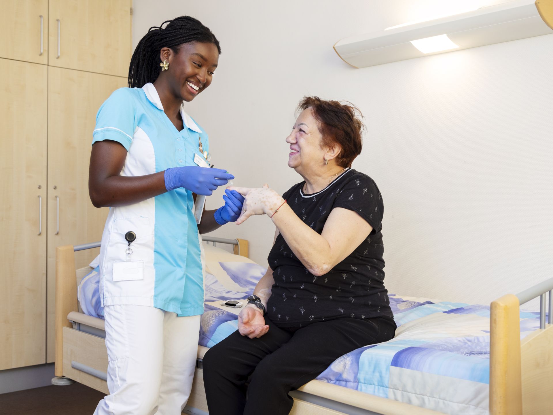 Stagiaire Chakira bloedsuiker meten bij Marja (clíënt)