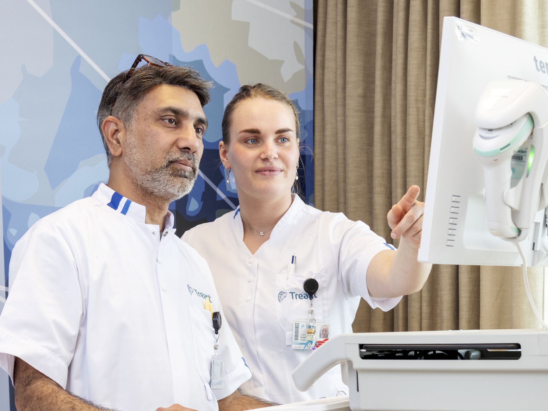 Zorgprofessionals bekijken gegevens op een computer naast een ziekenhuisbed