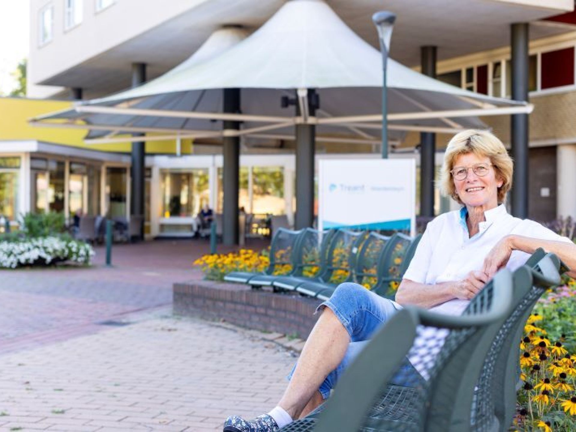 Jenny Hekman zit op het bankje voor woonzorglocatie Weidesteyn